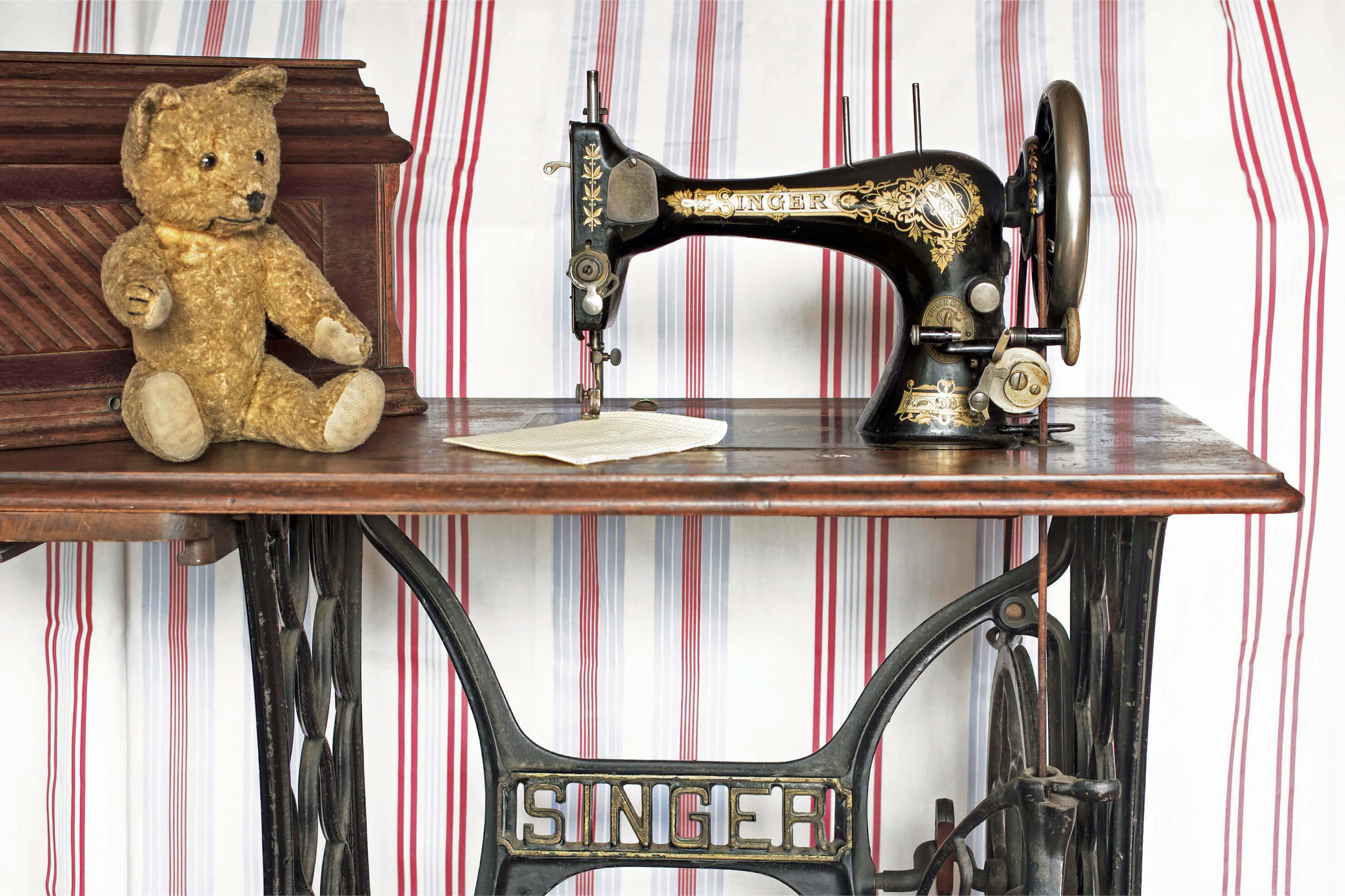 Vintage Singer treadle sewing machine. An old very loved teddy bear sits waiting for some clothes to be sewn