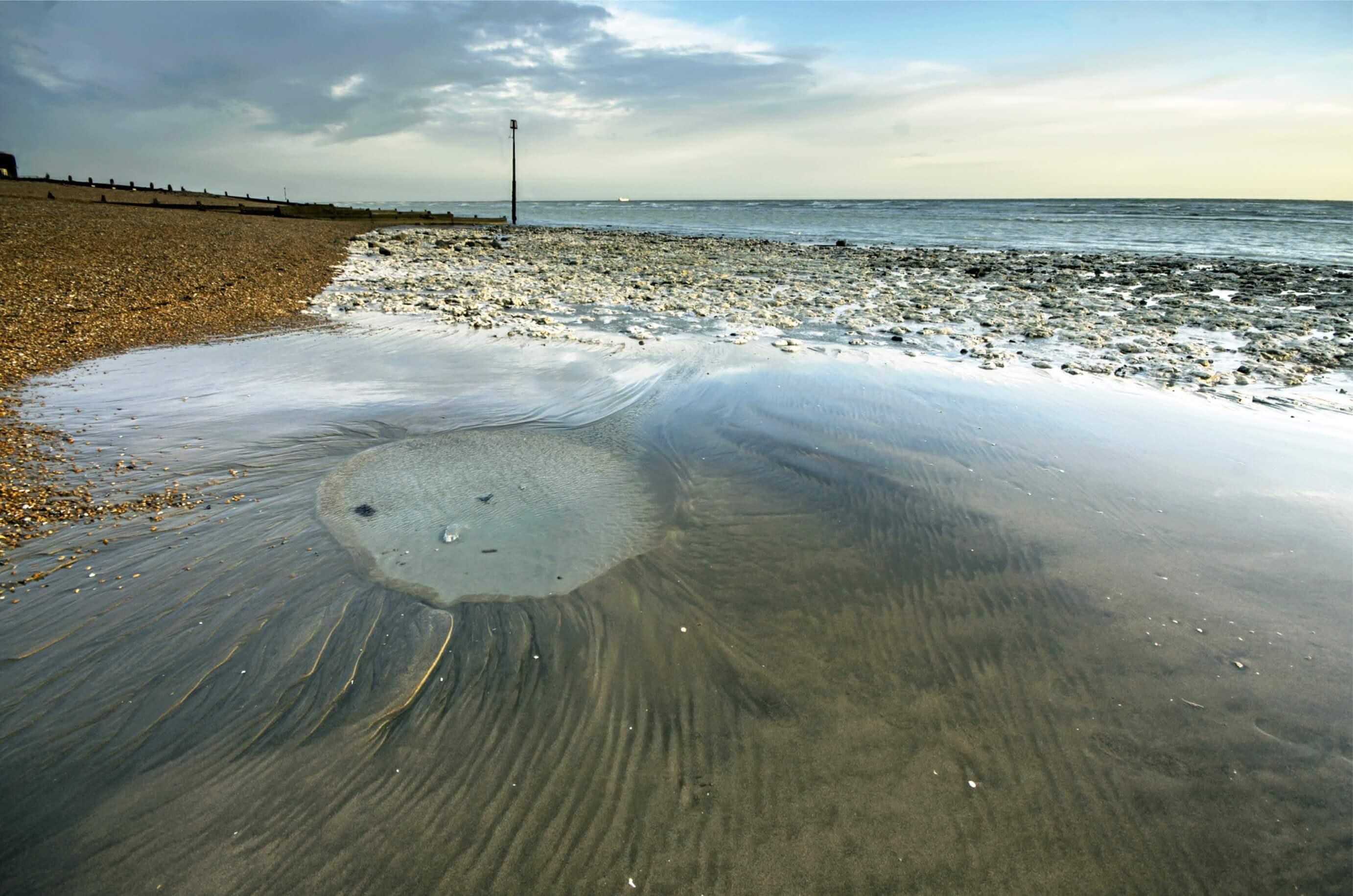 Oldstairs bay, in the sand is a large crater that looks like the moon, seaweed for eyes and mouth and a long chalk nose