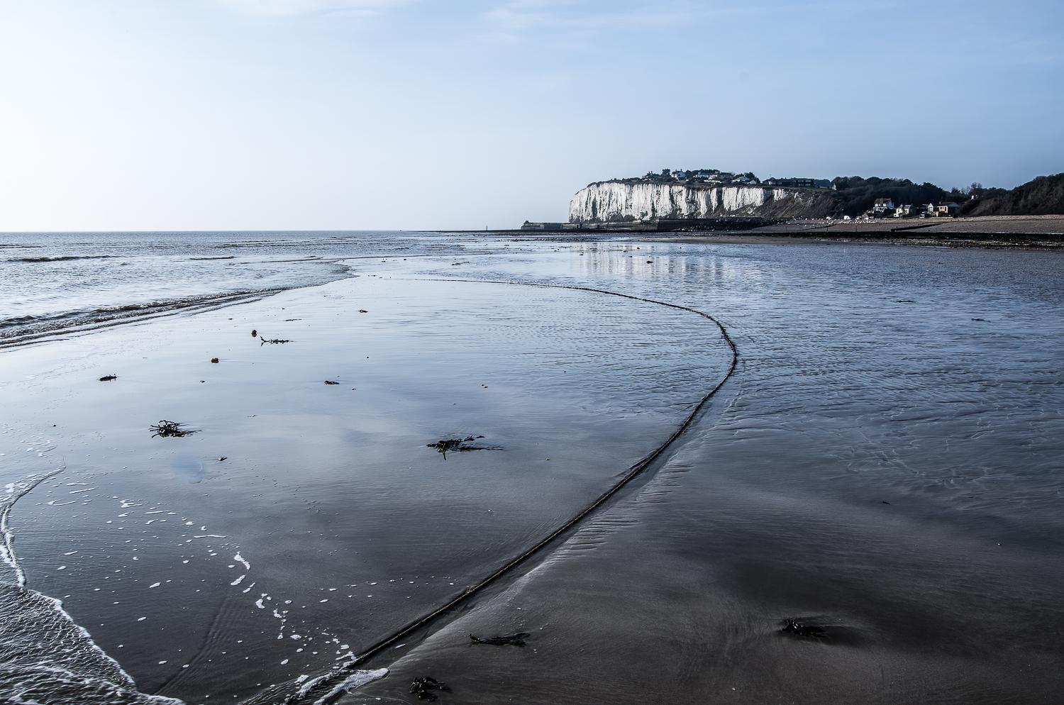 Kingsdown bay, A low spring tide has exposed a vast area of sand behind the seaweed covered chalk beds.