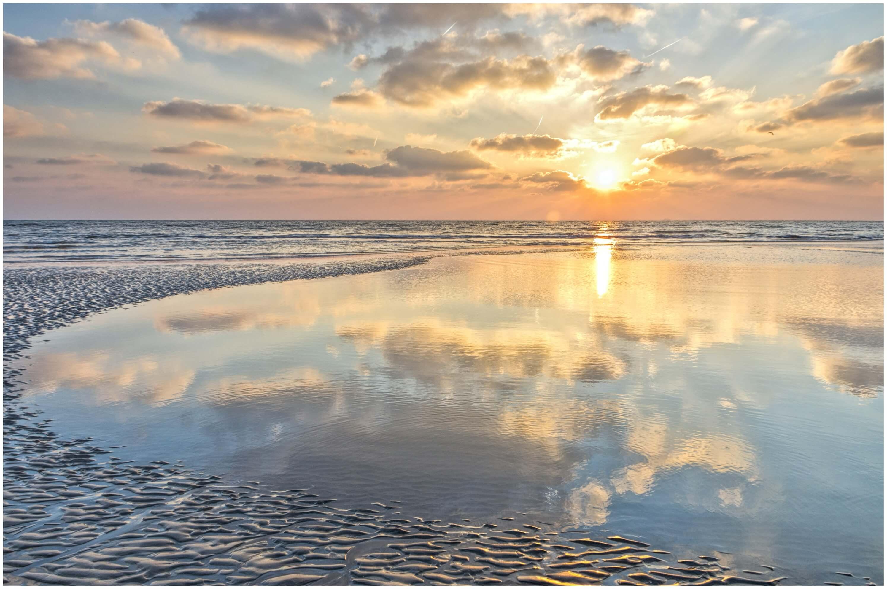 Sea captured in a tidal pool, Kingsdown Kent. Reflections of the sunrise and of puffy clouds in the pool.
