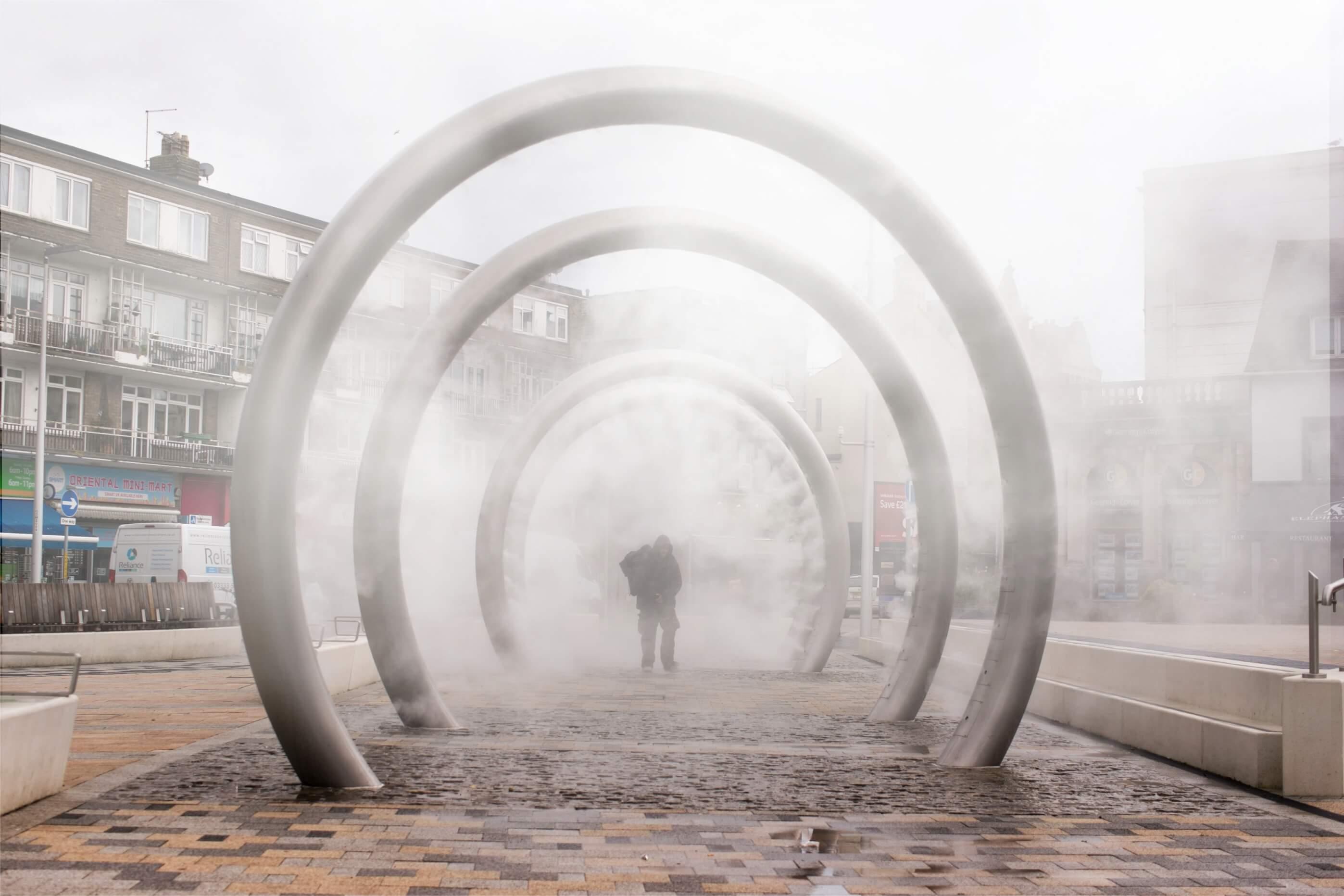 A walk through water sculpture, of 4 large metal hoops, each hoop sprays a fine mist into the surroundings